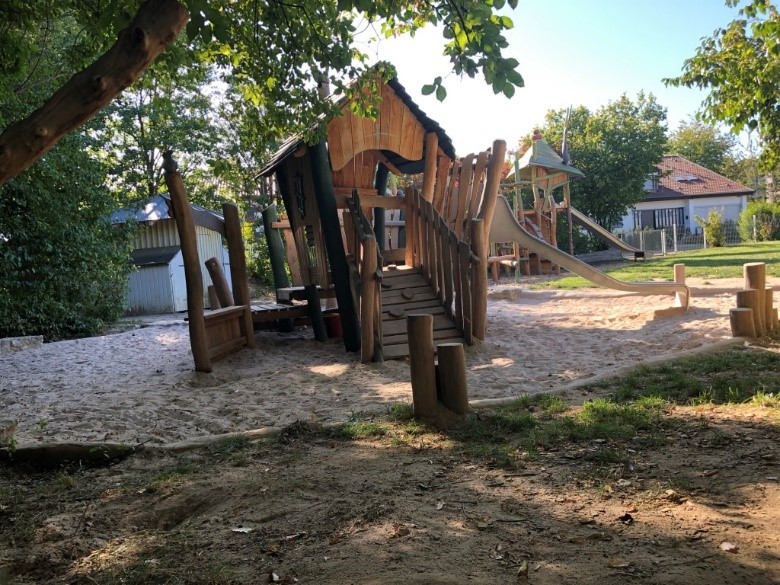 Im Sandkasten steht ein Klettergerüst mit integrierter Rutsche.