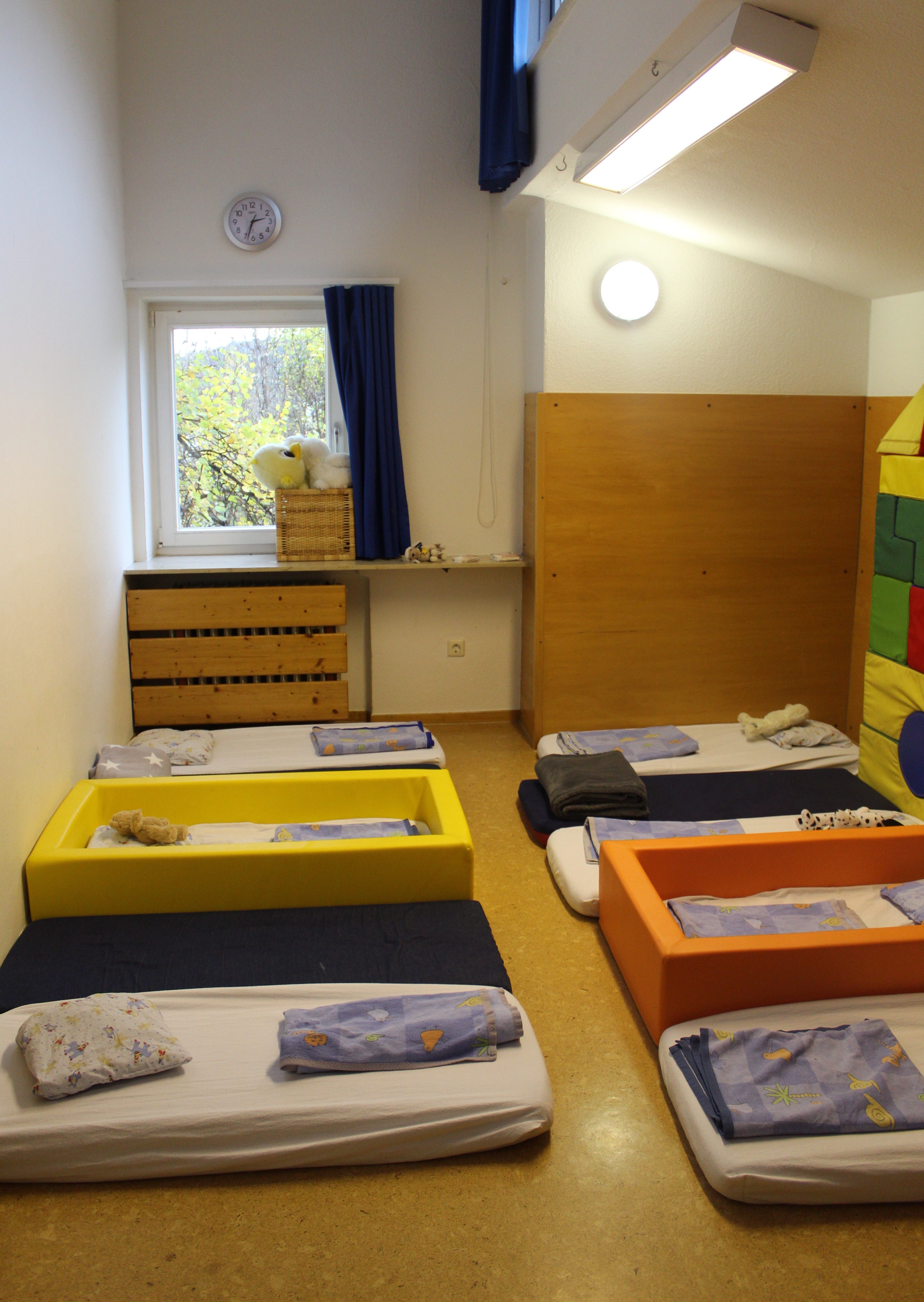 Das Bild zeig den Schlafraum der Krippengruppe. Es liegen 8 Matratzen mit blauer Bettwäsche auf dem Boden.