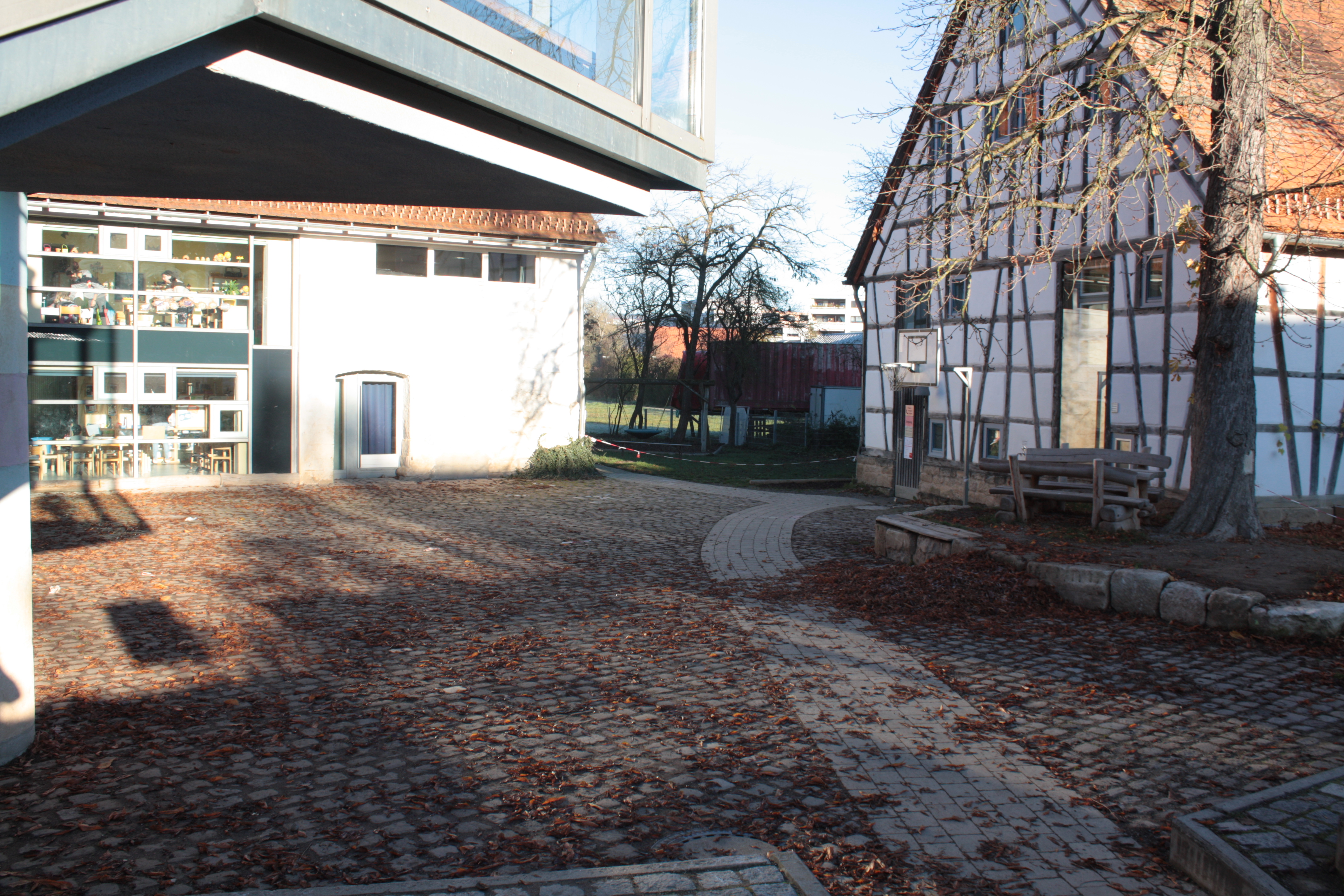 Die Außenansicht des Kinderhauses Alte Mühle aus einem anderen Winkel. Die Holzbank mit Tisch ist rechts abgebildet.