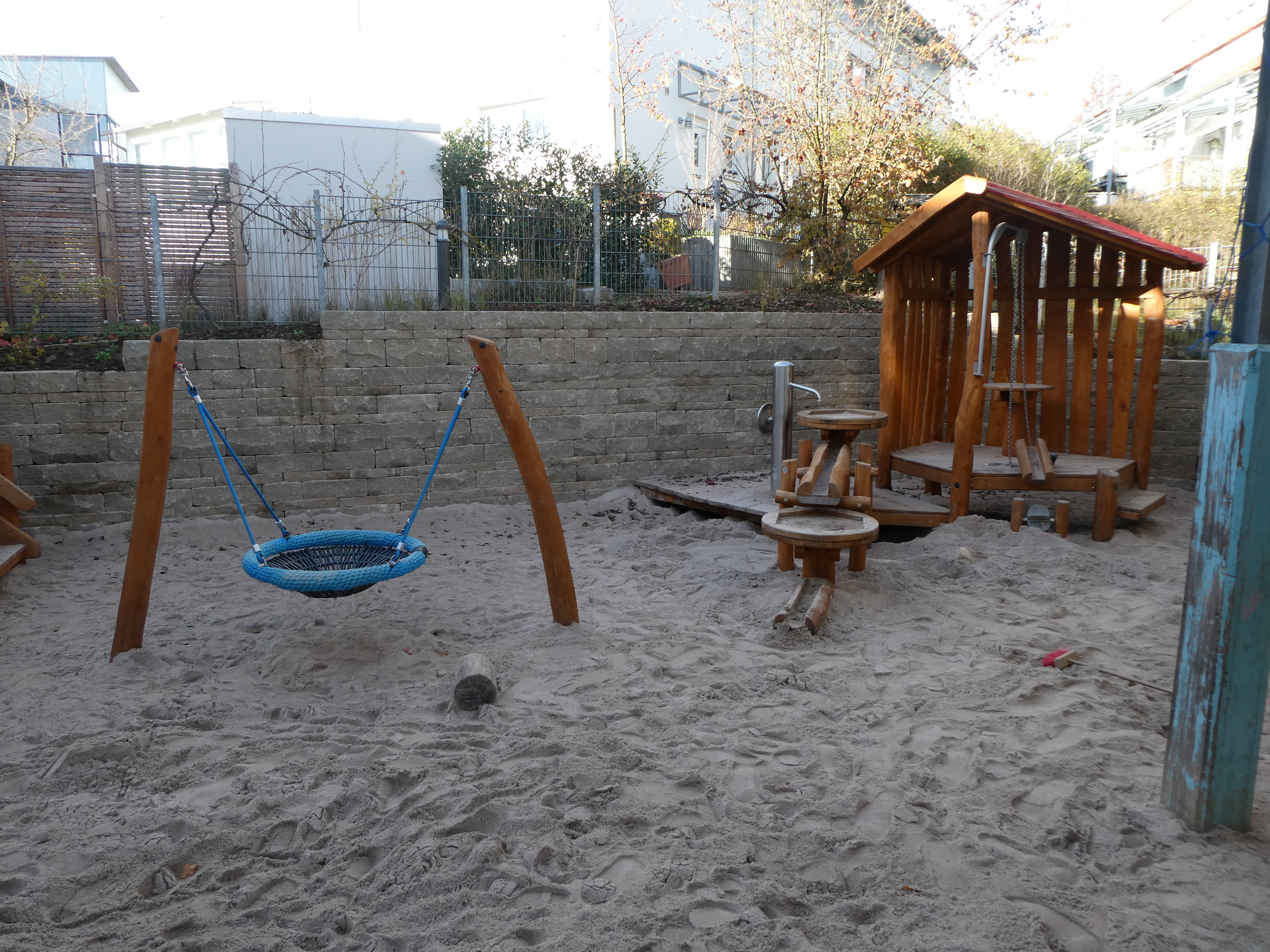 Sandspielbereich mit Schaukel und Wasserspiel