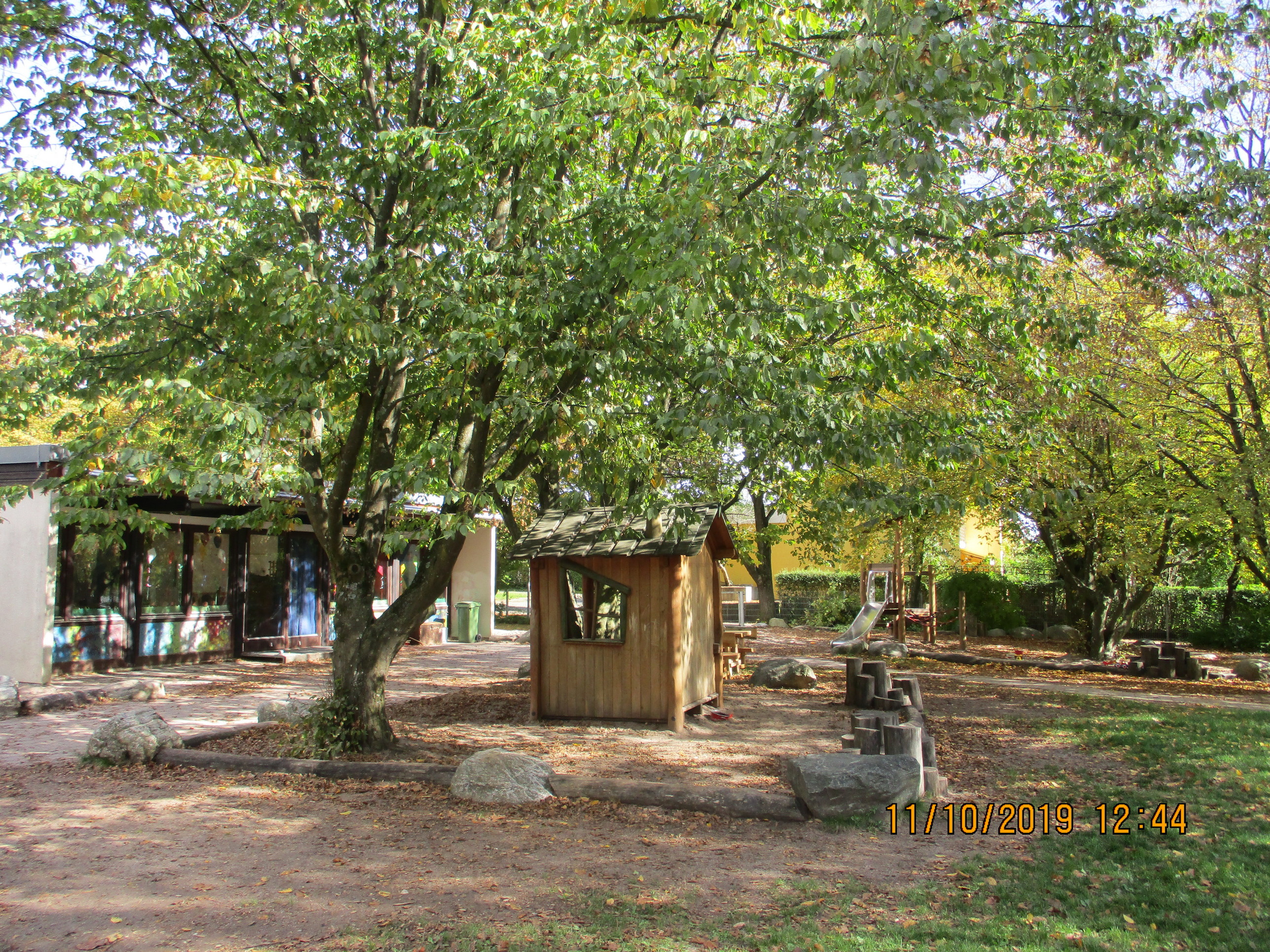 Großer Baum mit Spielhäuschen und Sandspielbereich