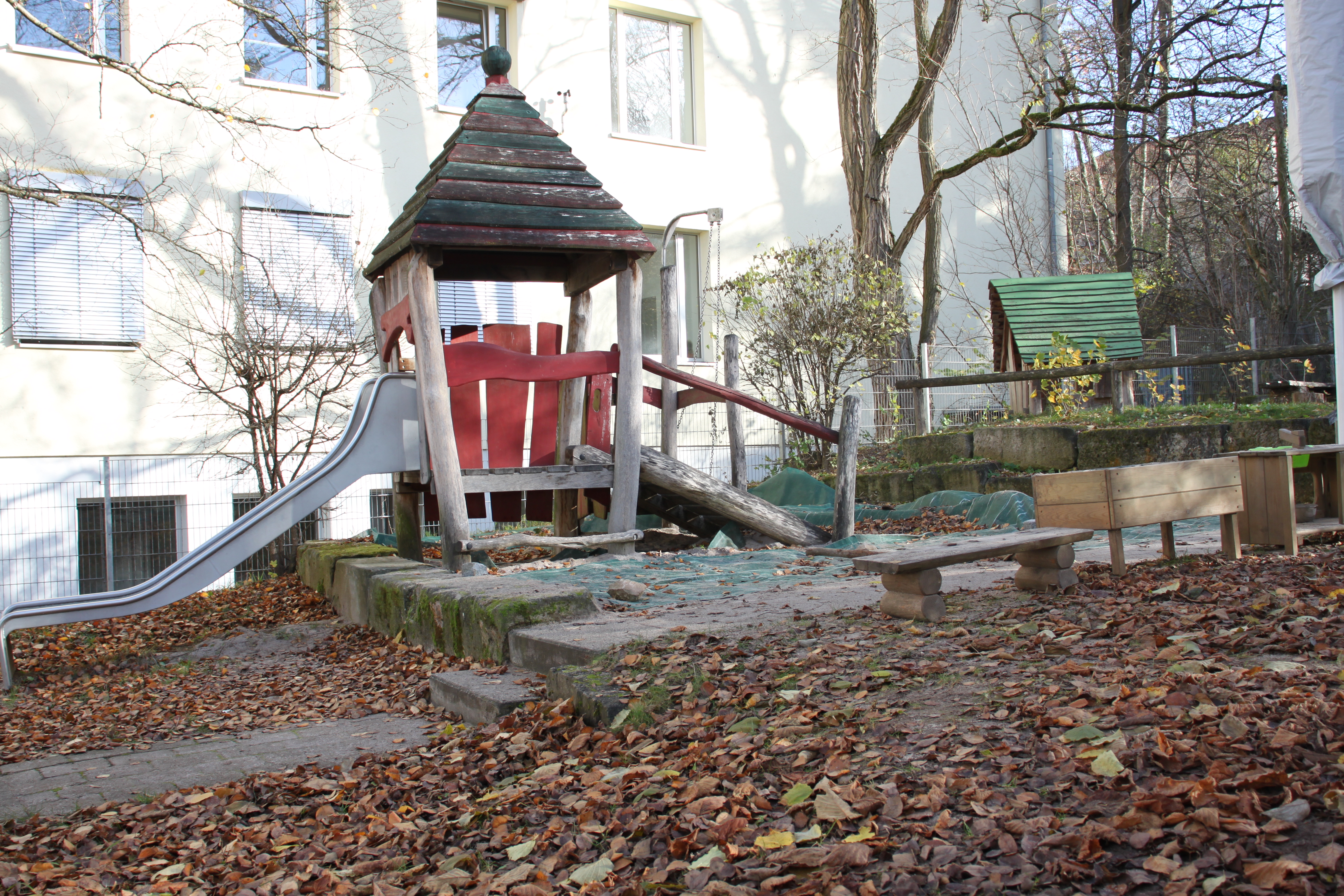 Es ein ein Spielhaus mit Rutschte und Sandkasten abgebildet.