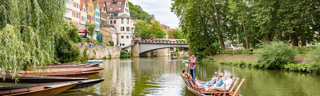 Ein Stocherkahn liegt auf dem Neckar, im Hintergrund die Neckarfront und Neckarbrücke