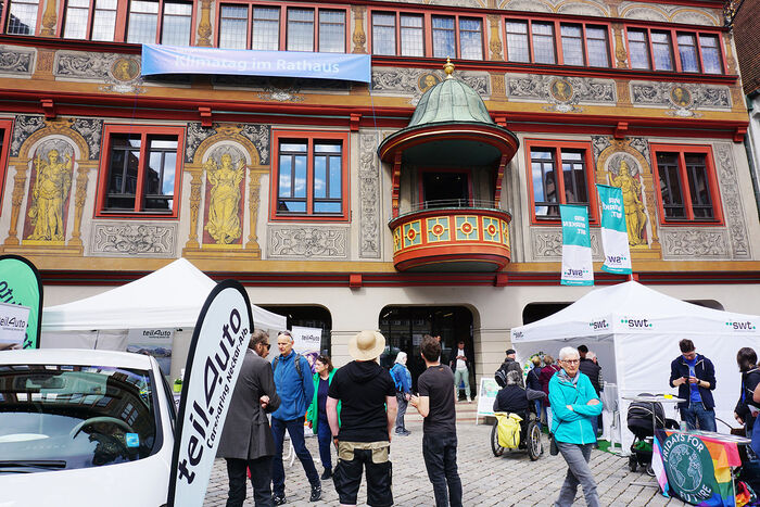 Man sieht das Tübinger Rathaus und Menschen und Stände (swt und teilAuto) davor.