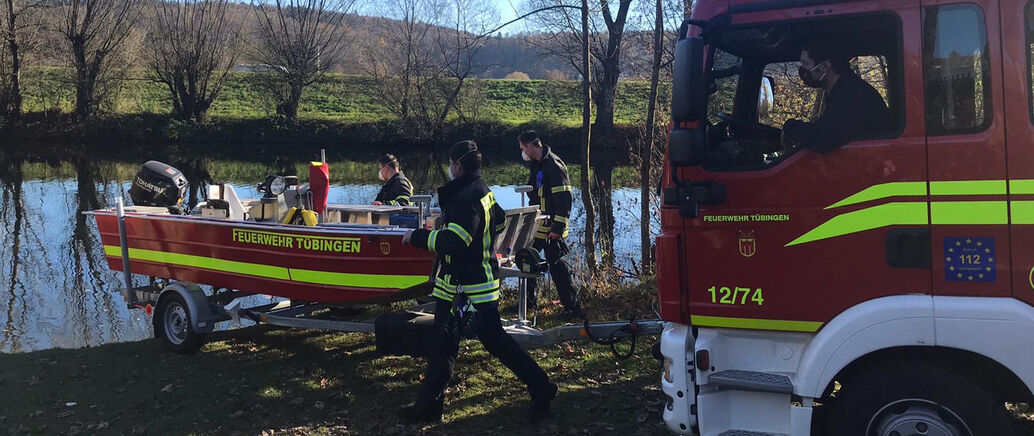 Feuerwehrleute tragen ein Boot zum Neckar.