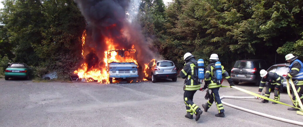 Feuerwehrmänner laufen zu einem brennenden Bus.