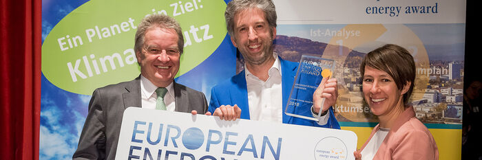 Landesumweltminister Franz Untersteller (links) und Charlotte Spörndli von der „Association European Energy Award AISBL“ (rechts) überreichen den European Energy Award in Gold im Februar 2019 an OB Boris Palmer (Mitte).