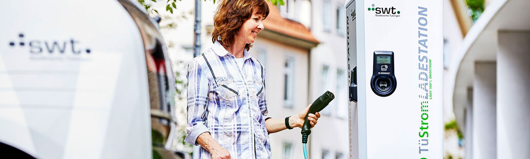 Frau steht vor einer Ladestation f&uuml;r E-Autos