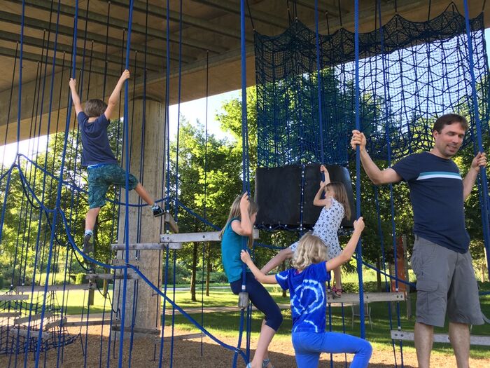 Kinder klettern an Seilen unter einer Br&uuml;cke