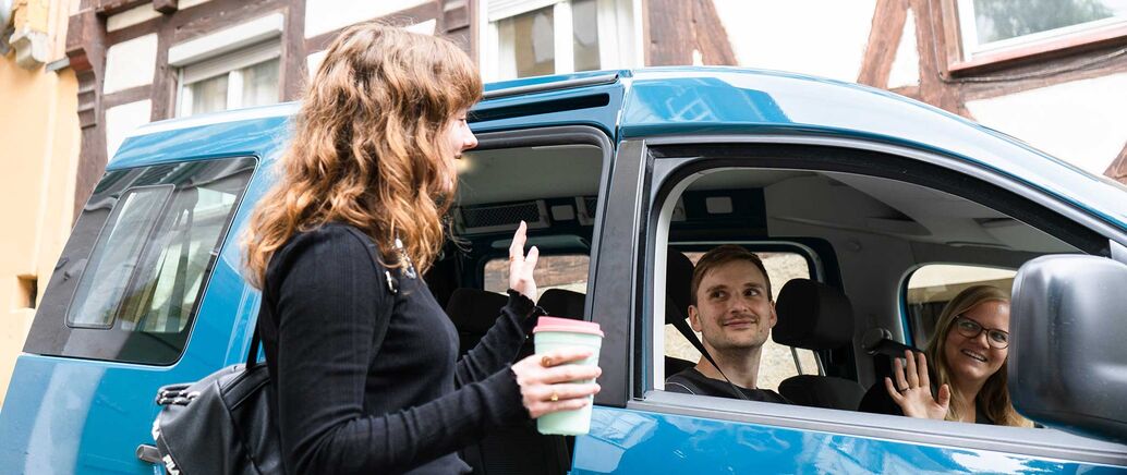 Drei Personen sind gemeinsam in einem Auto gefahren und verabschieden sich