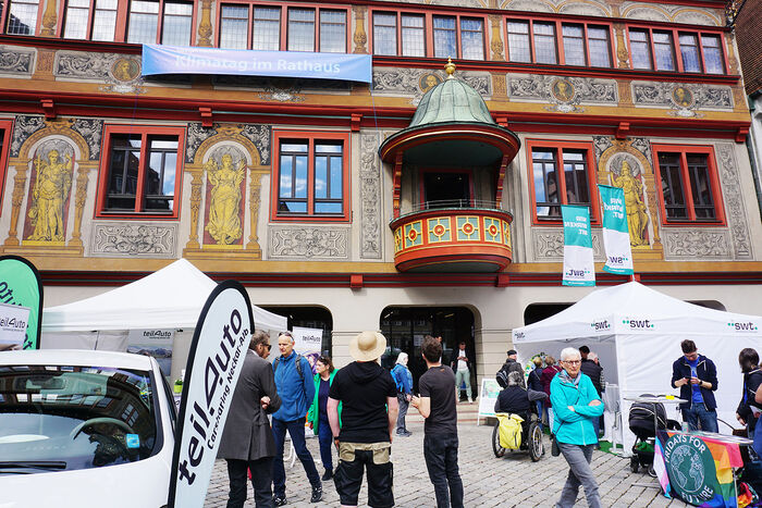 Man sieht das T&uuml;binger Rathaus und Menschen und St&auml;nde (swt und teilAuto) davor.