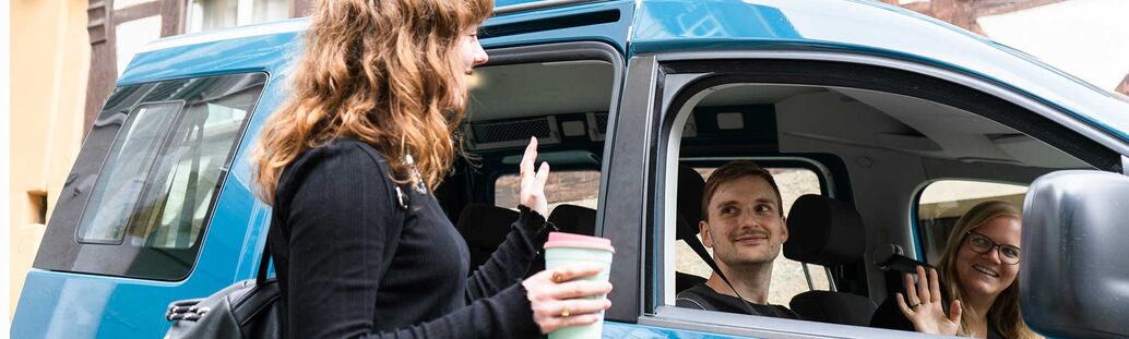 Drei Personen sind miteinander im Auto gefahren und verabschieden sich 