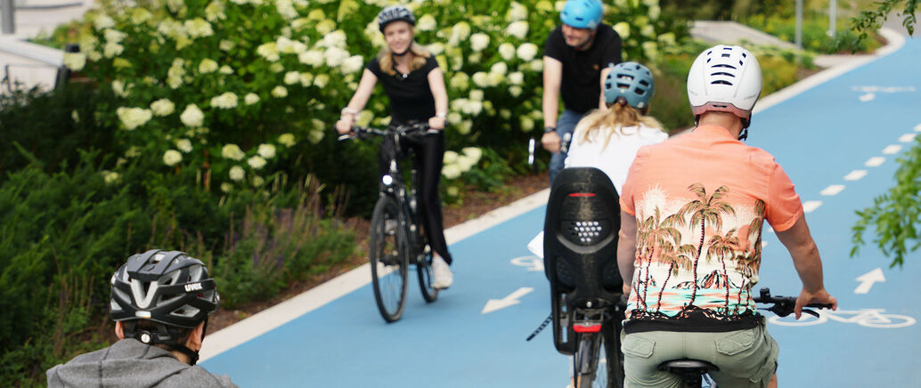 Radelnde Personen auf einem blauen Fahrradweg