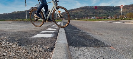 Eine Person auf einem Fahrrad f&auml;hrt &uuml;ber den abgesenkten Bordstein.