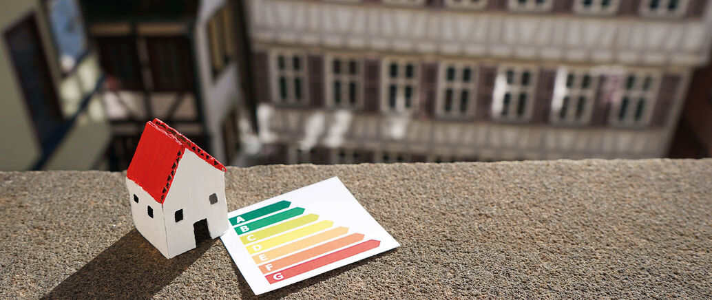 Gebasteltes Haus steht in der T&uuml;binger Altstadt auf einer Mauer, daneben eine Energie-Skala.