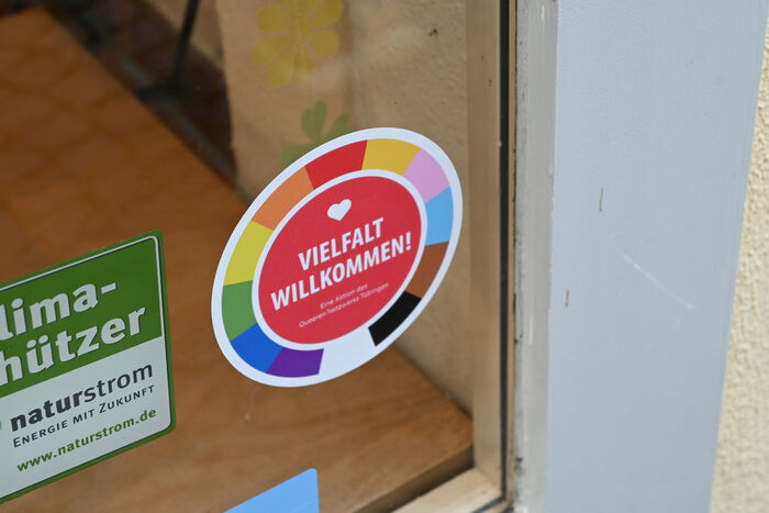 Runder Aufkleber in Regenbogenfarben mit Aufschrift "Vielfalt Willkommen" an einem Schaufenster